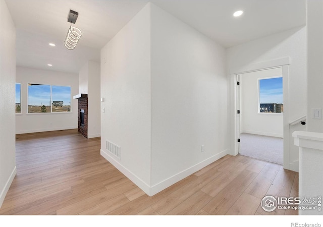 hallway with recessed lighting, light wood-style floors, visible vents, and baseboards