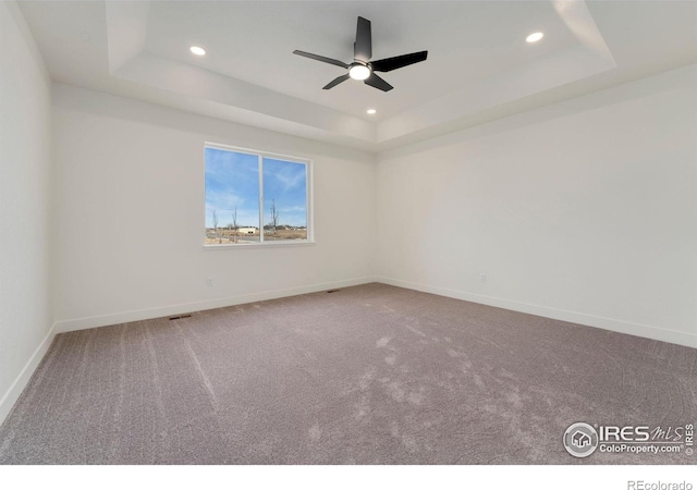 carpeted spare room with recessed lighting, baseboards, and a tray ceiling