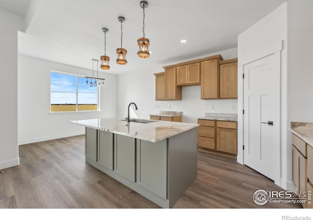 448 Cache Ave, Fort Morgan, CO 80701 - kitchen with a kitchen island with sink, brown cabinets, wood finished floors, a sink, and a notable chandelier