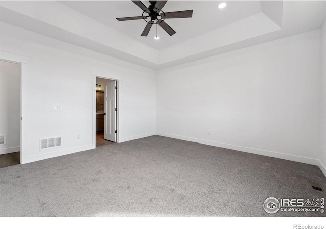 448 Cache Ave, Fort Morgan, CO 80701 - unfurnished bedroom featuring a tray ceiling, baseboards, visible vents, and dark carpet