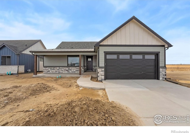 448 Cache Ave, Fort Morgan, CO 80701 - view of front of house featuring covered porch, stone siding, concrete driveway, an attached garage, and board and batten siding