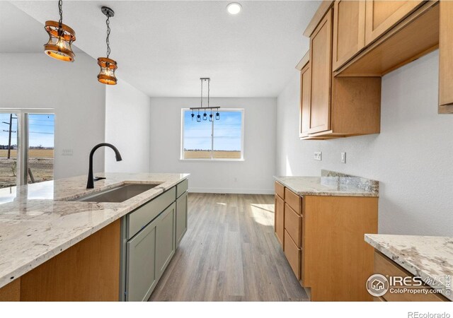 448 Cache Ave, Fort Morgan, CO 80701 - kitchen with light wood-style flooring, a sink, light stone counters, and pendant lighting