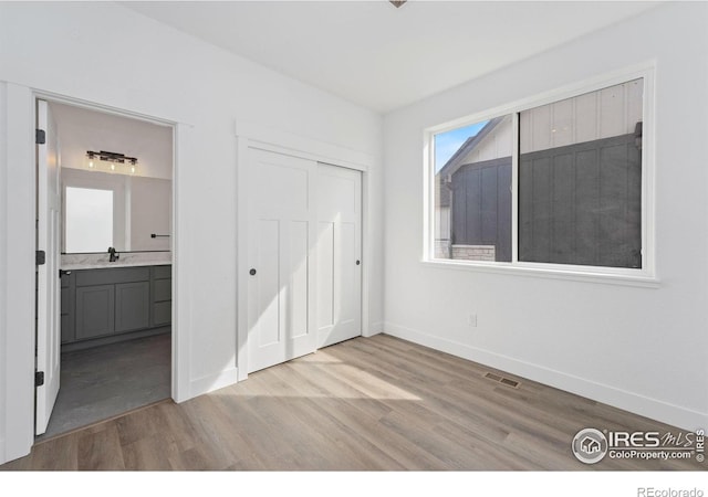 448 Cache Ave, Fort Morgan, CO 80701 - unfurnished bedroom with a closet, wood finished floors, ensuite bathroom, baseboards, and visible vents
