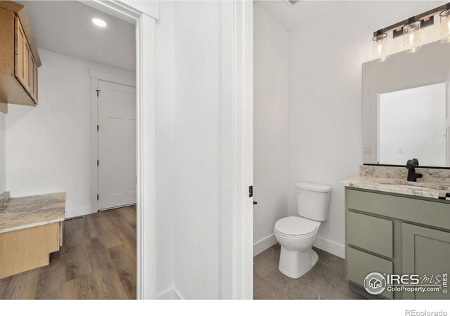 448 Cache Ave, Fort Morgan, CO 80701 - bathroom featuring baseboards, toilet, vanity, and wood finished floors