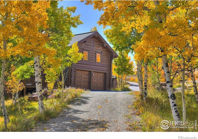 view of home's exterior with log exterior, an attached garage, and driveway