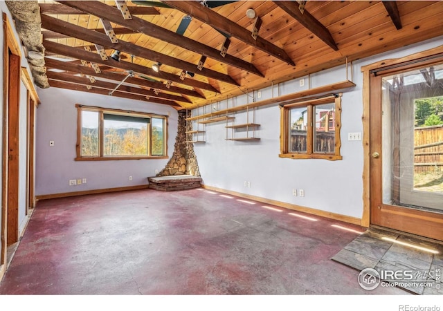 unfurnished living room with beamed ceiling, wood ceiling, and a healthy amount of sunlight