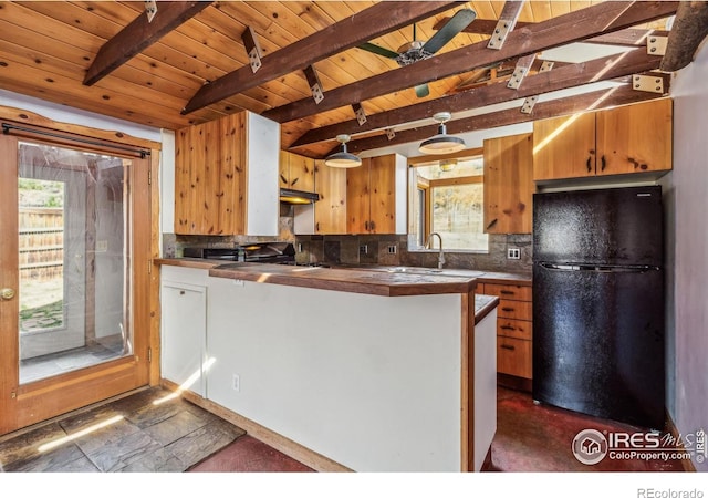 kitchen with beamed ceiling, sink, kitchen peninsula, black refrigerator, and decorative backsplash