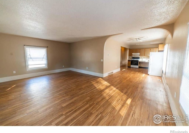 unfurnished living room featuring ceiling fan, a textured ceiling, and light hardwood / wood-style floors