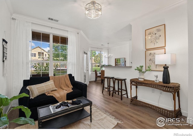 living room featuring crown molding, hardwood / wood-style floors, and a chandelier