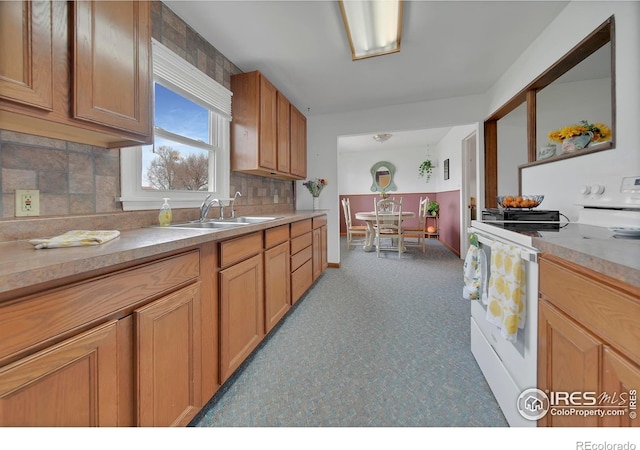 kitchen featuring white stove, sink, and backsplash