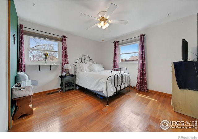 bedroom with ceiling fan, hardwood / wood-style flooring, and multiple windows