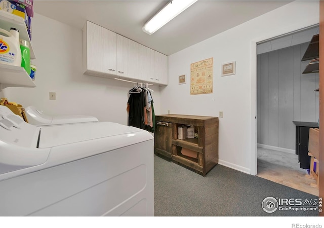 clothes washing area with dark colored carpet, washer and clothes dryer, and cabinets