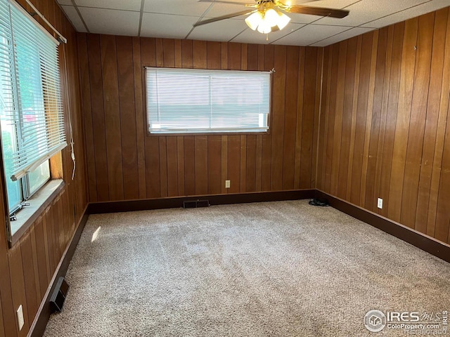 spare room with a paneled ceiling, carpet flooring, a wealth of natural light, and ceiling fan