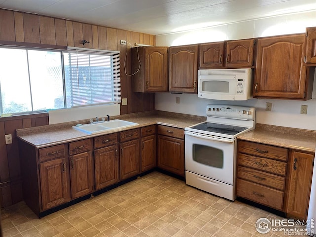 kitchen with wood walls, white appliances, sink, and plenty of natural light