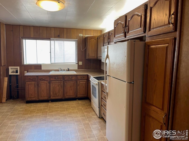 kitchen with wooden walls, sink, and white appliances