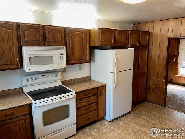 kitchen featuring wooden walls, white appliances, and a textured ceiling