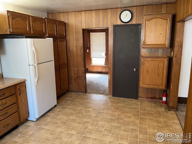 kitchen with light carpet, wood walls, and white fridge