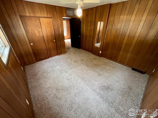 unfurnished bedroom with wood walls, a closet, and carpet flooring