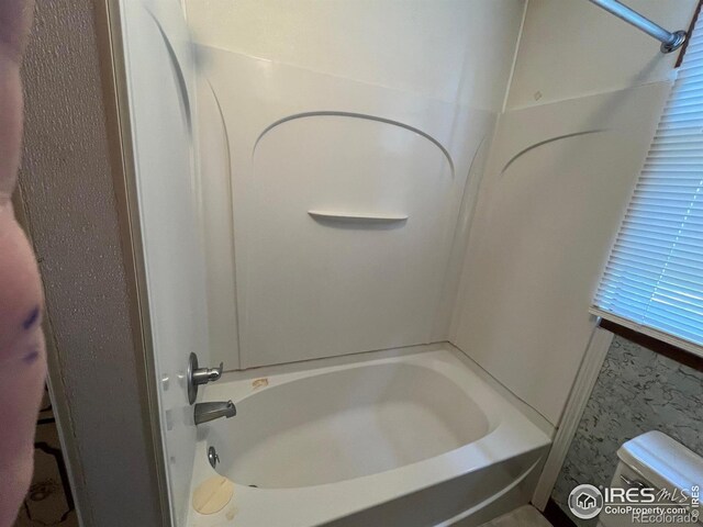 bathroom featuring tub / shower combination and toilet