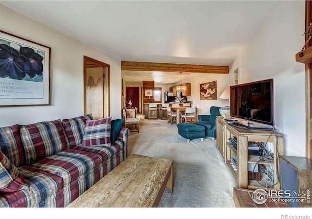 carpeted living room featuring beamed ceiling and an inviting chandelier