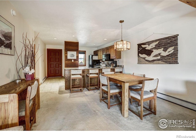 carpeted dining space with a notable chandelier and a baseboard heating unit