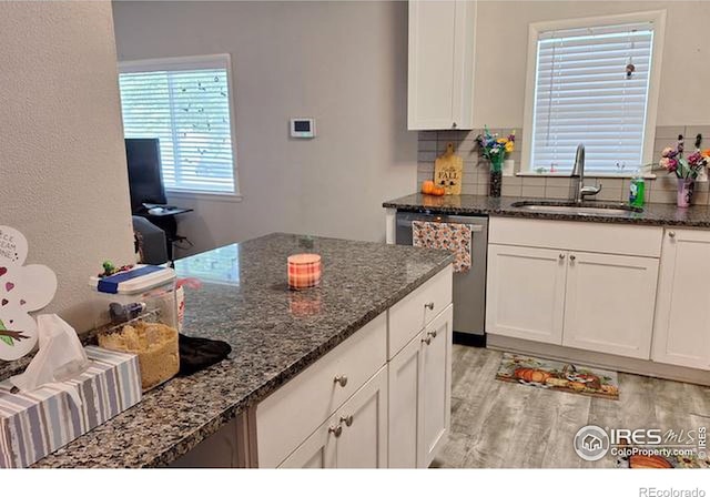 kitchen featuring white cabinets, sink, dishwasher, dark stone countertops, and decorative backsplash