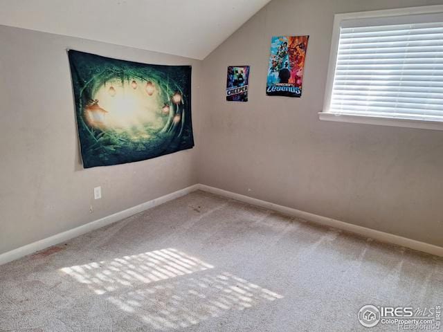 carpeted empty room with vaulted ceiling