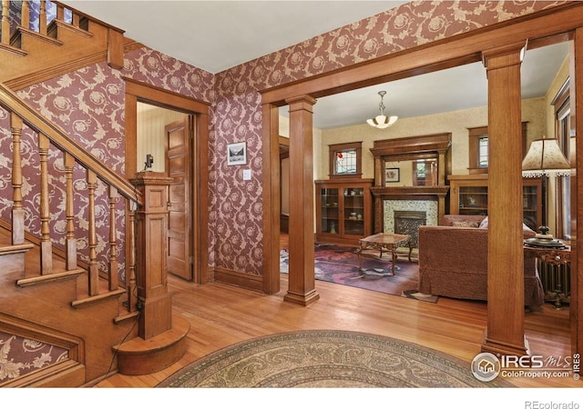 foyer featuring an inviting chandelier, hardwood / wood-style flooring, plenty of natural light, and ornate columns