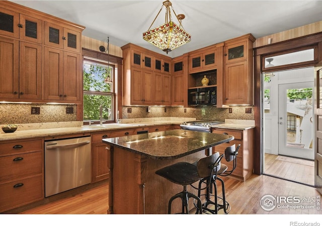 kitchen featuring stainless steel appliances, dark stone countertops, sink, and a center island