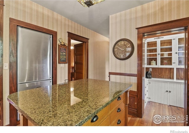 kitchen featuring light wood-type flooring, stone countertops, and a center island