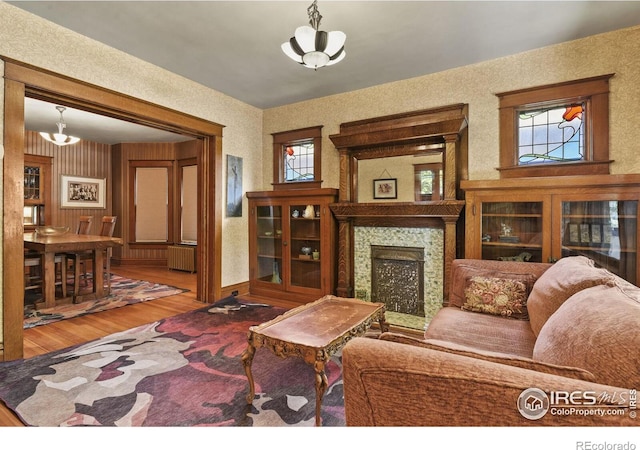 living room featuring a high end fireplace, radiator heating unit, hardwood / wood-style floors, and a wealth of natural light