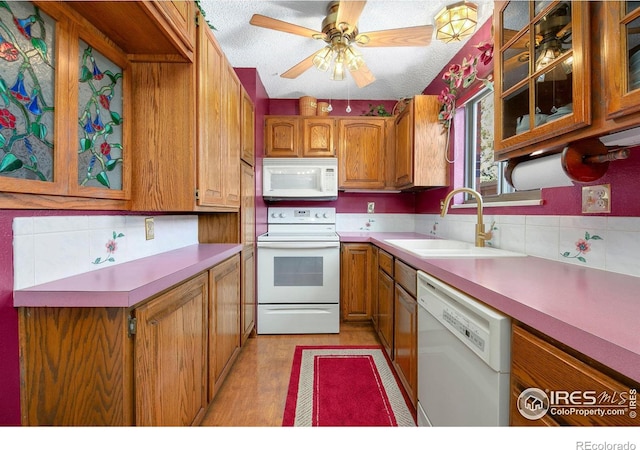 kitchen with decorative backsplash, a textured ceiling, sink, and white appliances