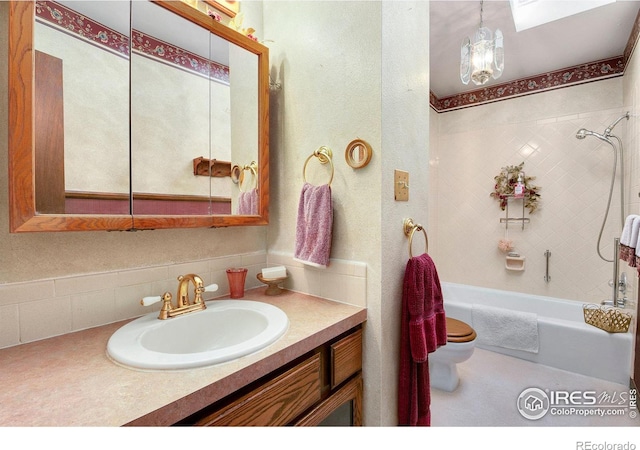 full bathroom with vanity, toilet, a chandelier, and tiled shower / bath