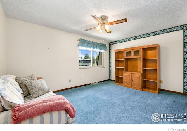 unfurnished room with a textured ceiling, carpet, and ceiling fan