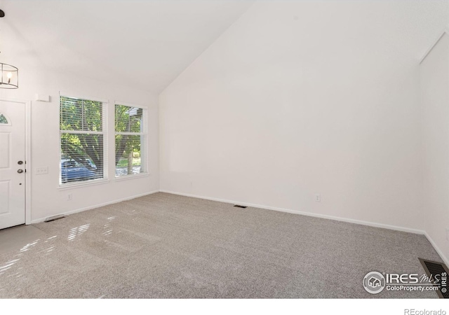 unfurnished room with vaulted ceiling, an inviting chandelier, and light carpet