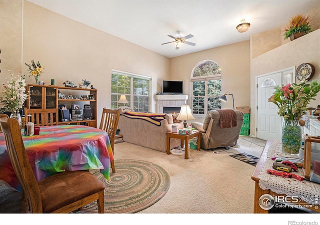 carpeted living room featuring ceiling fan, a tile fireplace, and a healthy amount of sunlight