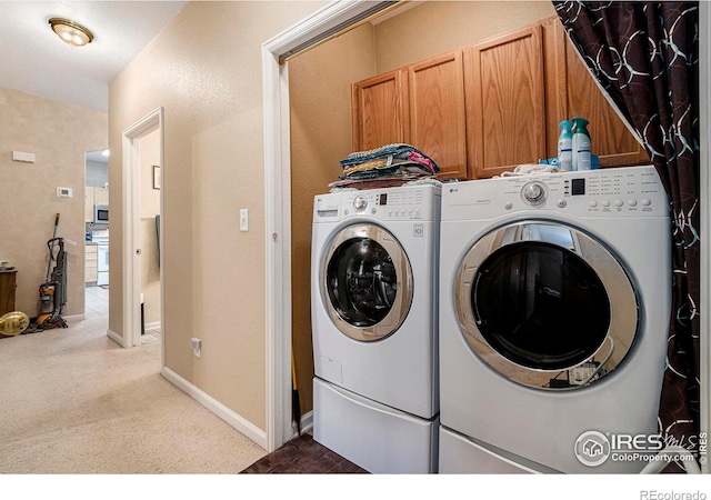 clothes washing area featuring washer and dryer, light colored carpet, and cabinets