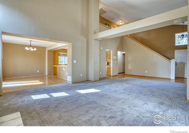 unfurnished living room featuring high vaulted ceiling, carpet floors, and an inviting chandelier