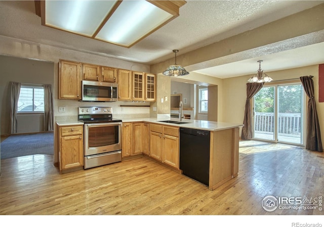 kitchen with light hardwood / wood-style floors, sink, kitchen peninsula, hanging light fixtures, and appliances with stainless steel finishes