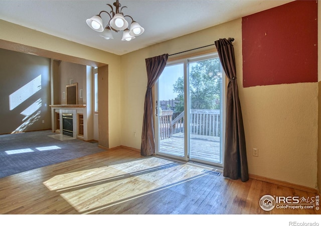 doorway with a chandelier, hardwood / wood-style floors, and a tiled fireplace