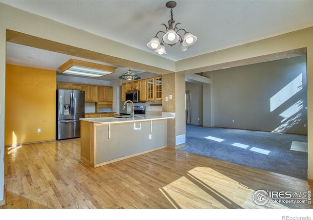 kitchen with sink, kitchen peninsula, light hardwood / wood-style flooring, a chandelier, and stainless steel appliances