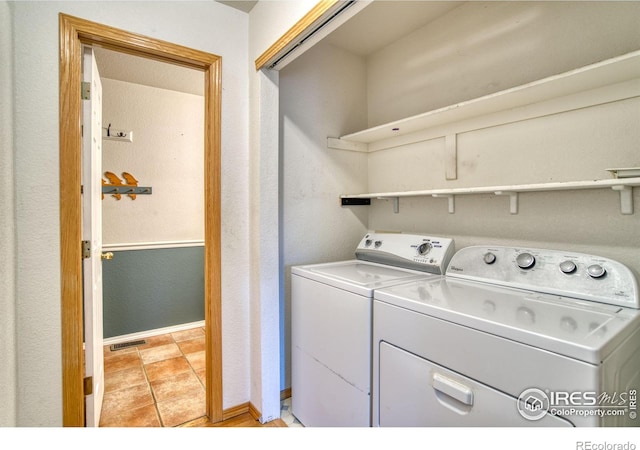 clothes washing area featuring light tile patterned flooring and washing machine and clothes dryer