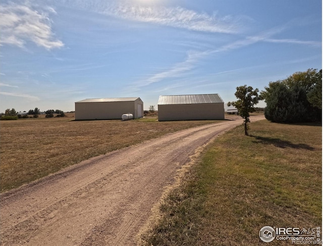 view of street featuring an outbuilding, a rural view, and dirt driveway