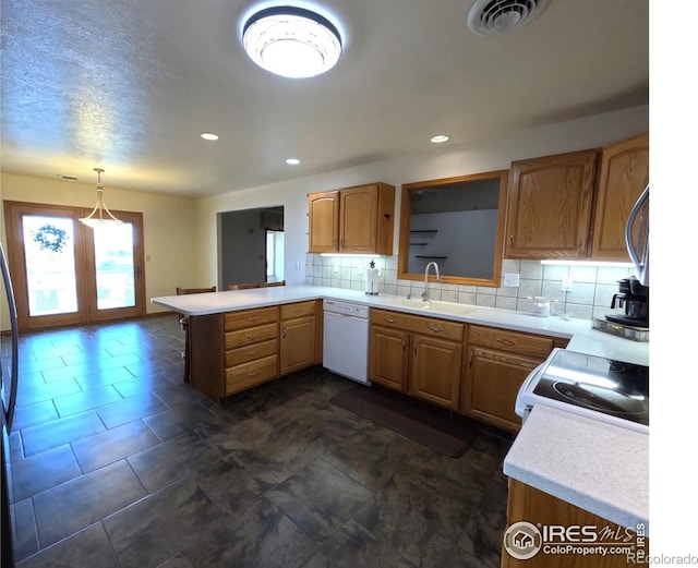 kitchen featuring visible vents, a sink, backsplash, white appliances, and a peninsula