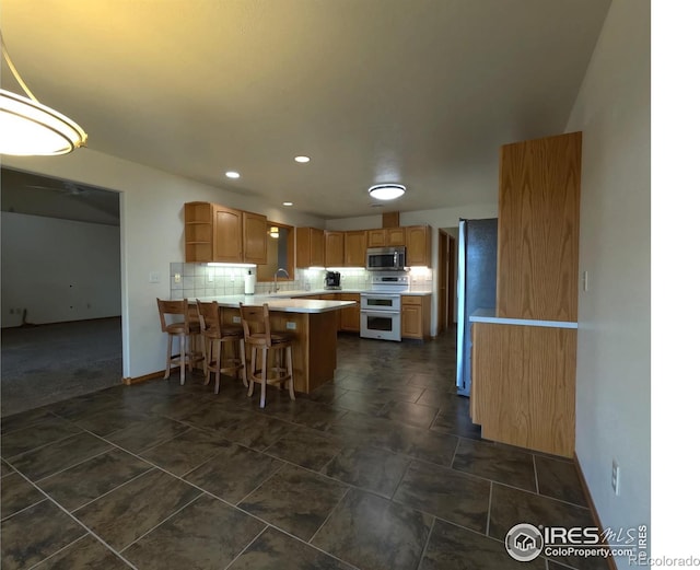 kitchen featuring open shelves, a peninsula, a sink, stainless steel appliances, and tasteful backsplash