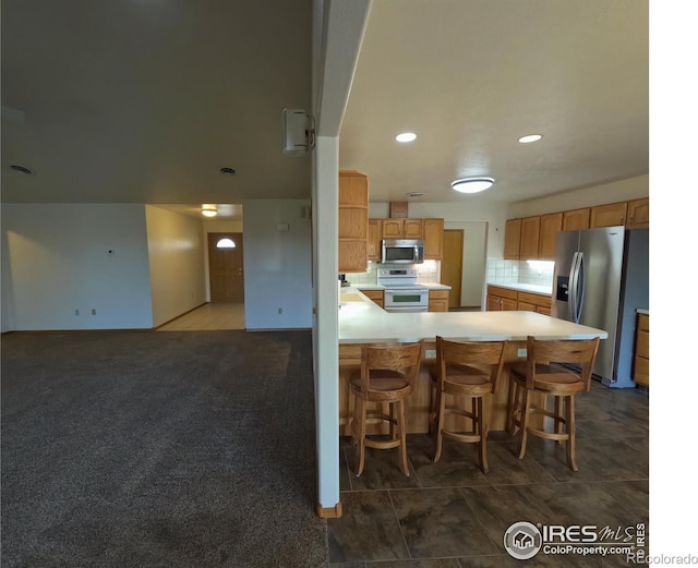 kitchen featuring light countertops, carpet floors, decorative backsplash, a peninsula, and stainless steel appliances