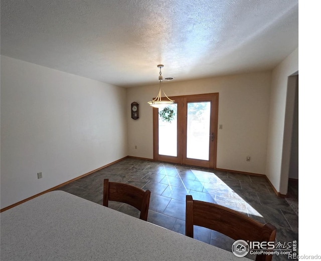 interior space featuring tile patterned flooring, a textured ceiling, and baseboards