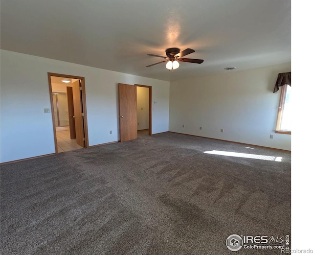 carpeted empty room featuring a ceiling fan and baseboards