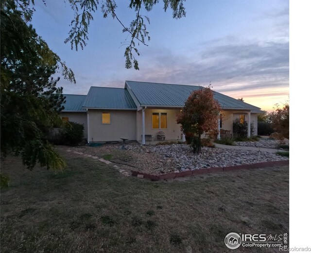 single story home featuring stucco siding, metal roof, and a lawn