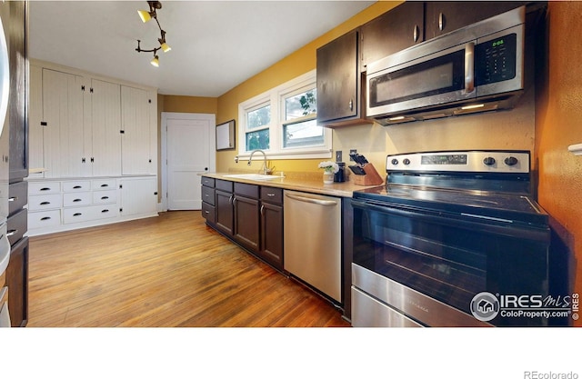 kitchen with light hardwood / wood-style flooring, dark brown cabinetry, stainless steel appliances, and sink